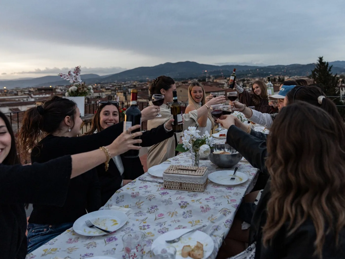 Friends toasting around a long table on the rooftop
